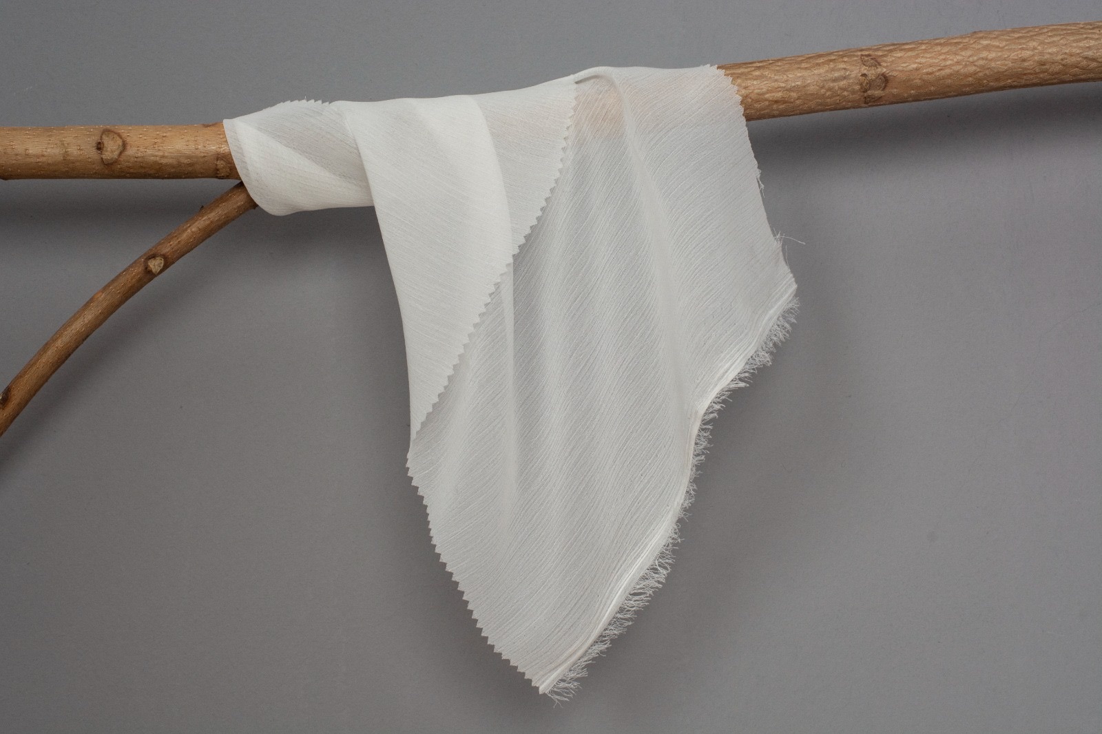 Greige white crepe draped over a wooden branch